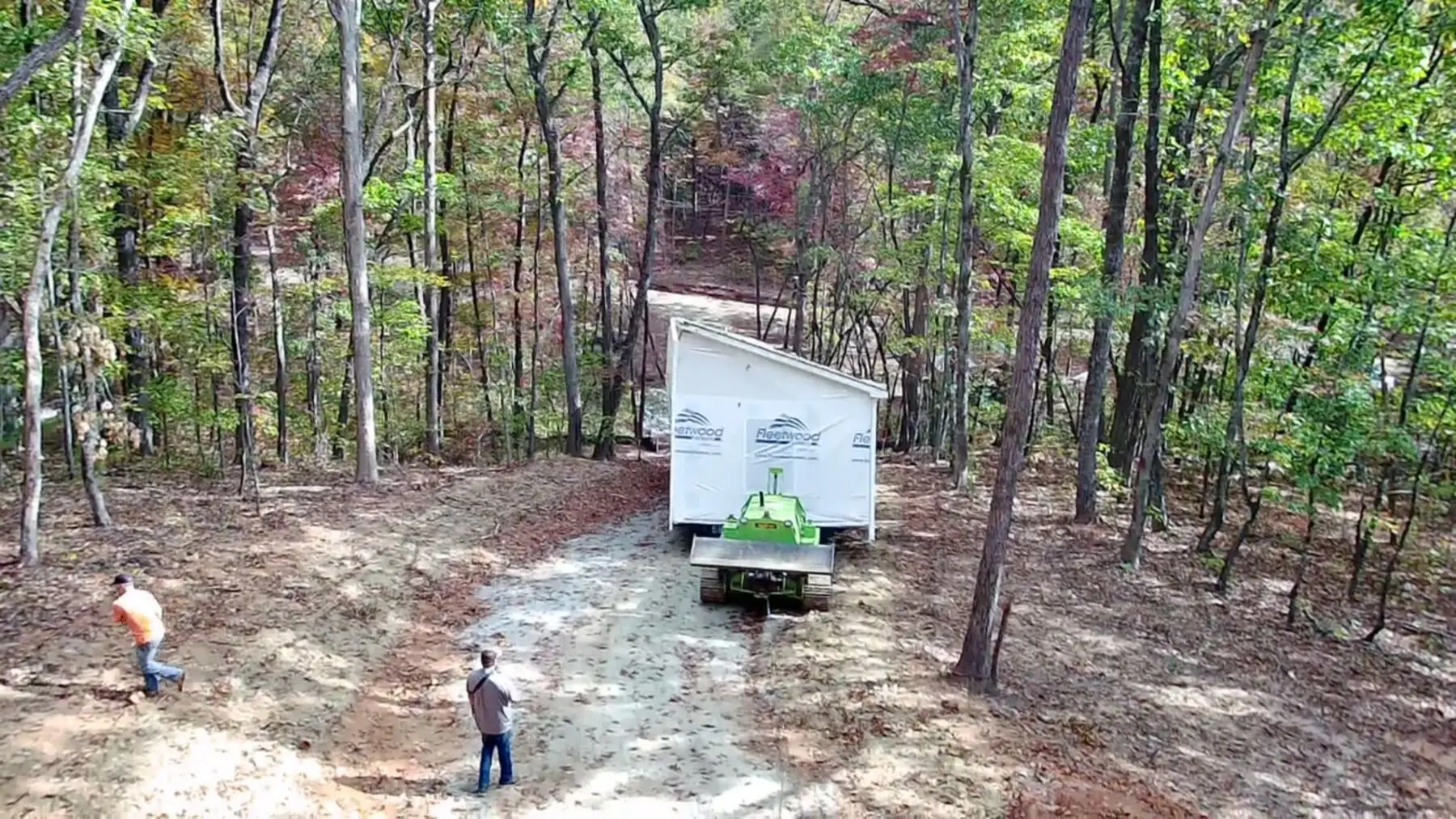 Aerial house tug moving home through woods.