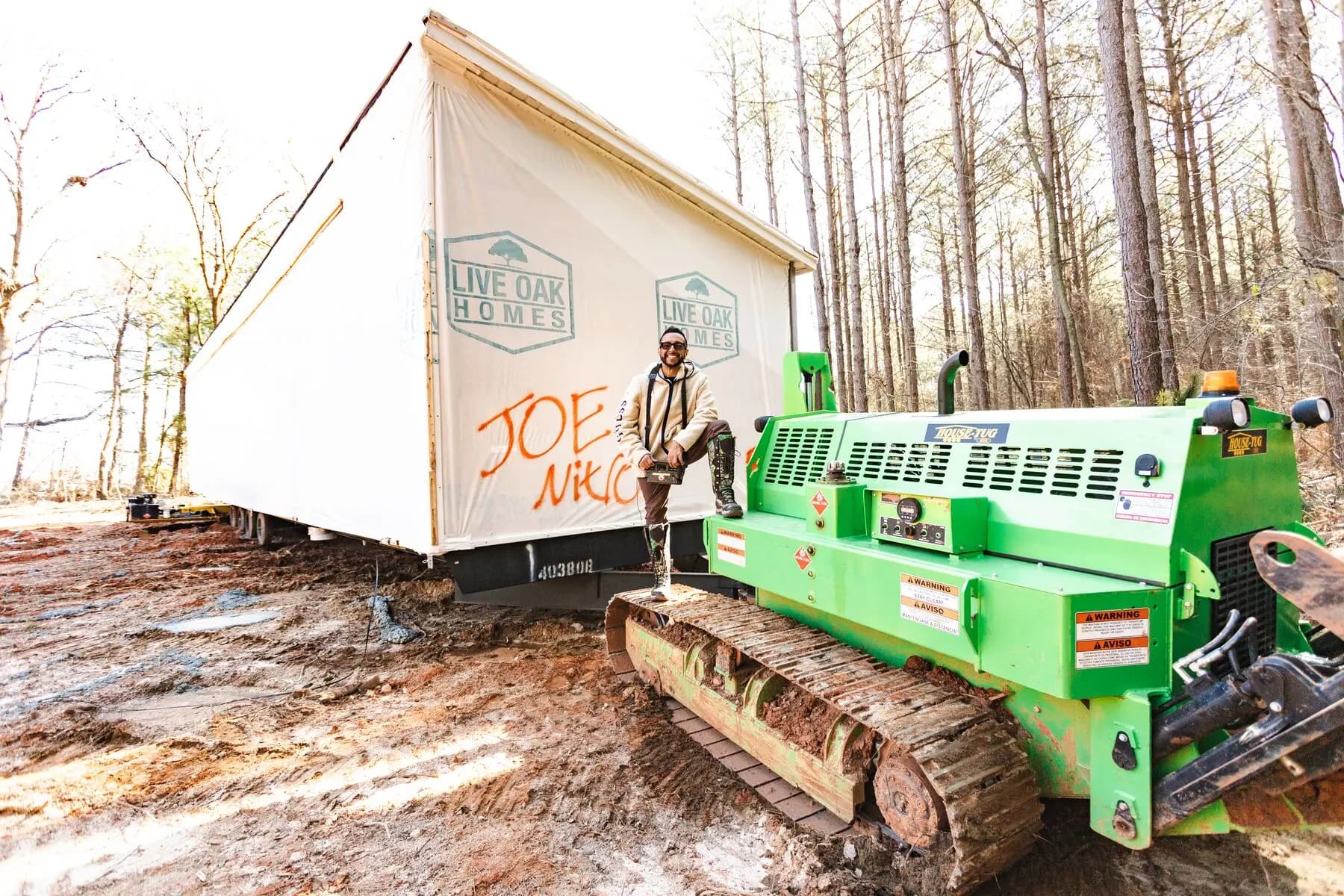 House tug guiding home through wooded site.