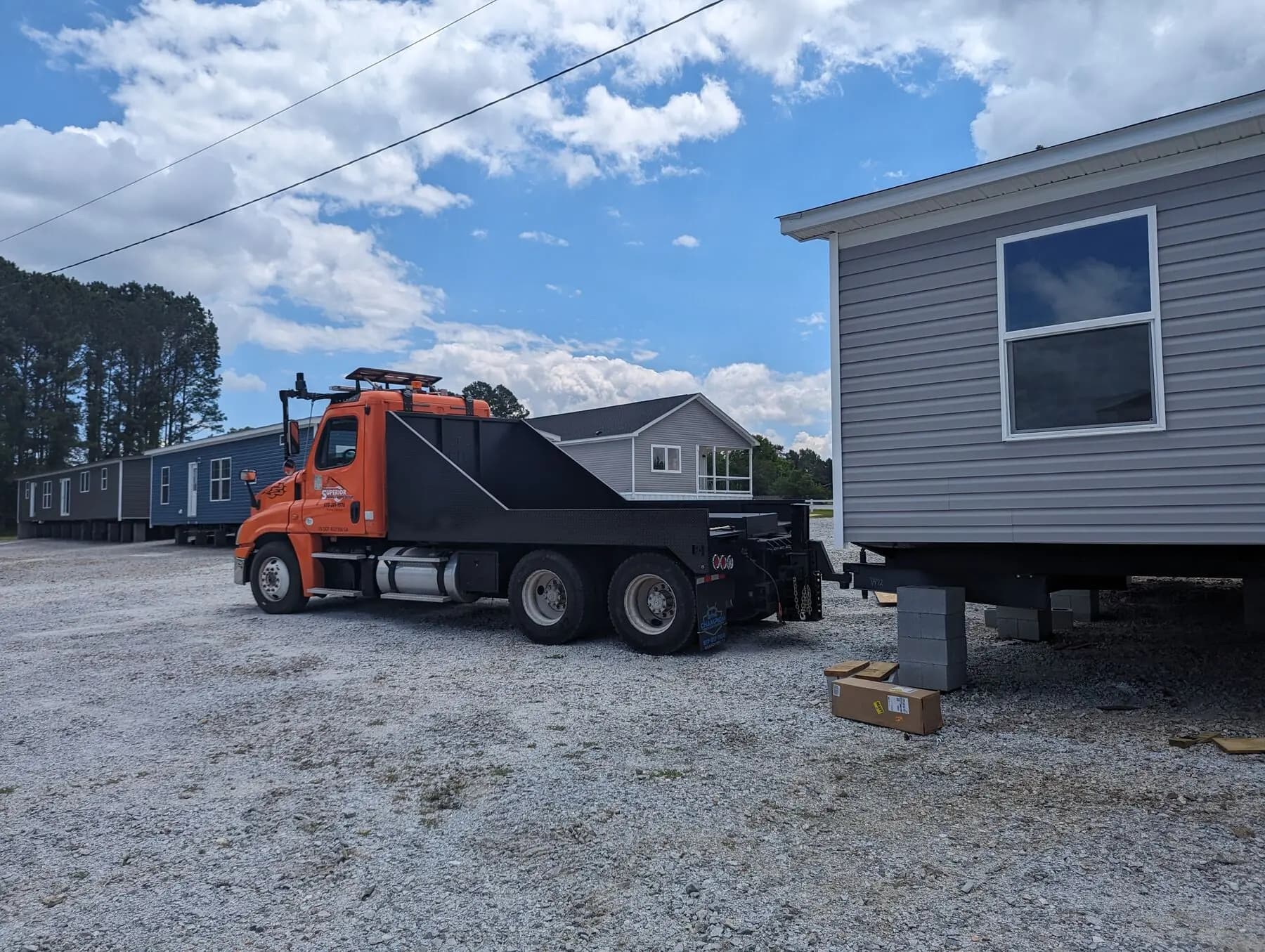 Orange truck transporting manufactured home.